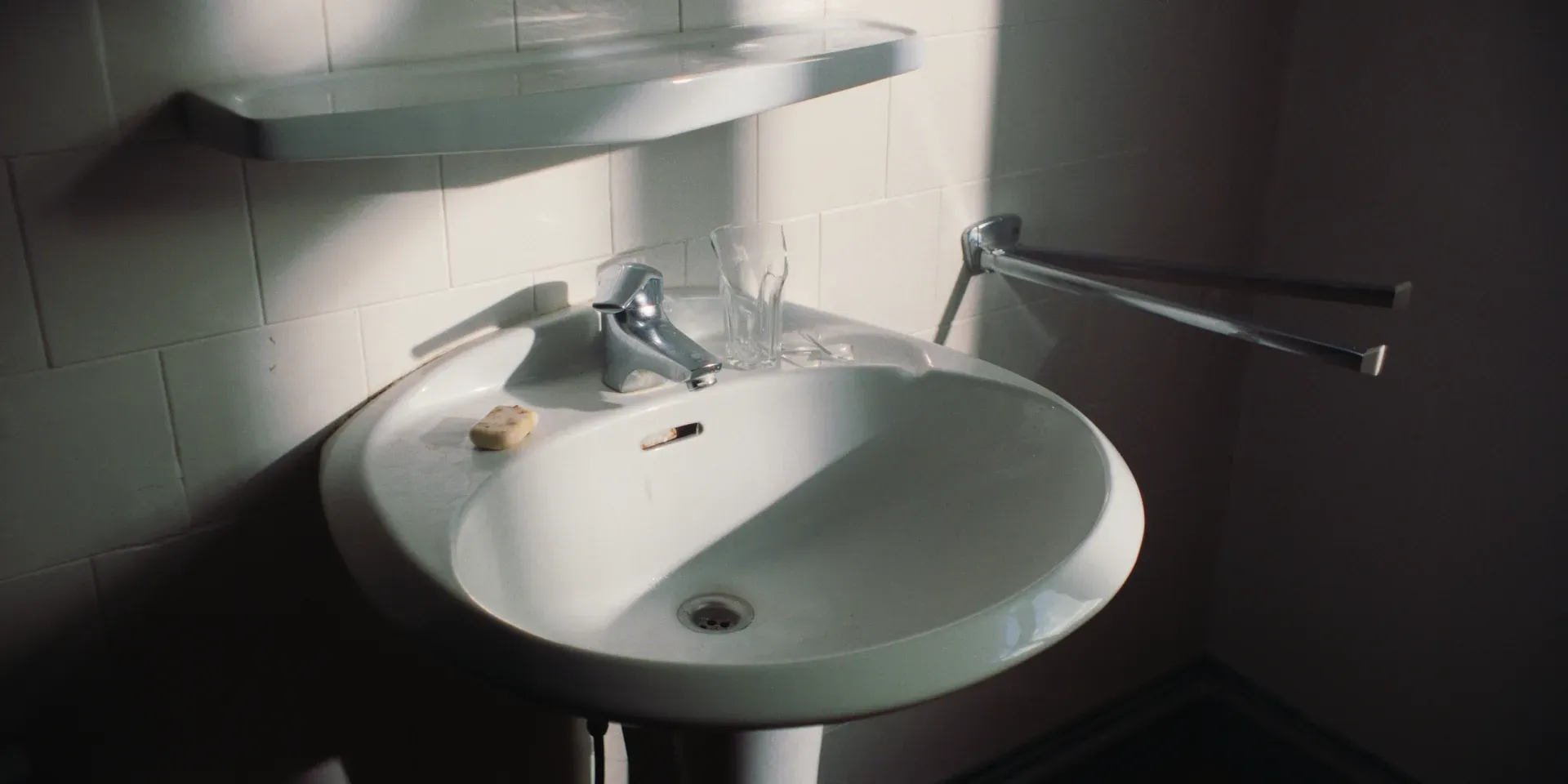 A sunlit bathroom sink with soap and a drinking glass in The Tears of Things