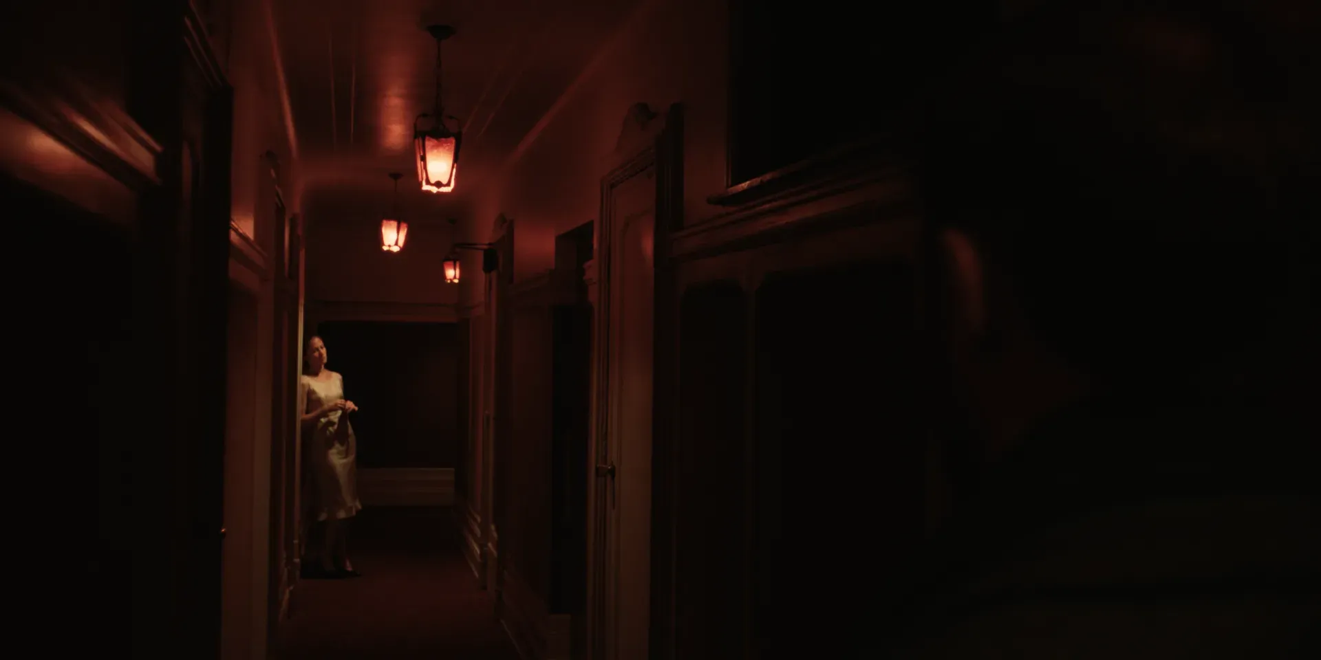 Ana appearing in the doorway of a red-lit hallway in The Tears of Things